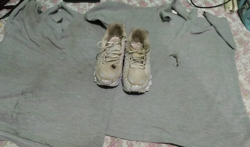 Camiseta e tênis queimados em cima de uma cama.